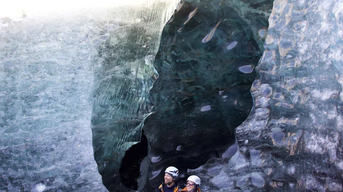 Visitors strapping on crampons at the edge of Breiðamerkurjökull on an easy glacier hike near the Vatnajökull ice caves, Iceland